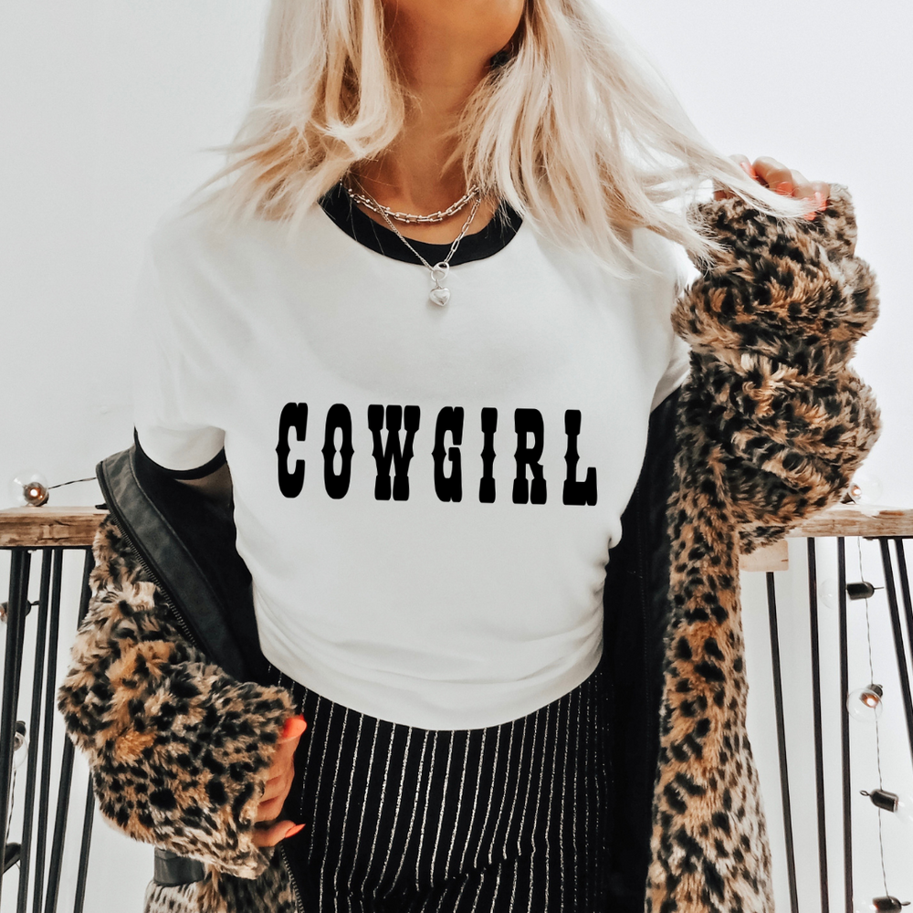 Close up of blonde model wearing a white ringer tee with Cowgirl text printed on the front